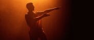 A silhouette of a man dancing in orange light