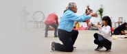 A young girl and an older man meet in the middle of a performance space on bended knee