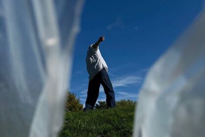 A man dances in a field. The edges of the frame are covered bya plastic material