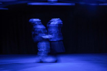 Two people meet in a blue light. the photo is blurred.