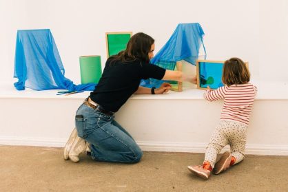 A young person plays with colourful scarves and scrap items