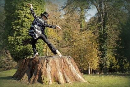 A woman dressed as a woodpecker on a tree stump