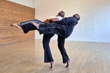 Two older black female dancers move in unison in a studio