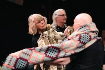 A group of older dancers leave fabric aorund their arms as they move