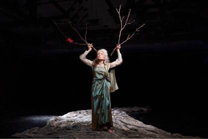 A woman stands in a river of silk with two sticks to her head like antlers