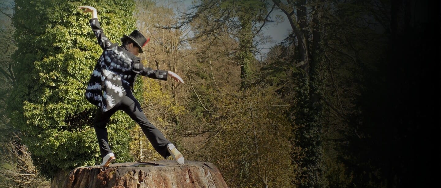 A woman dressed as a woodpecker on a tree stump