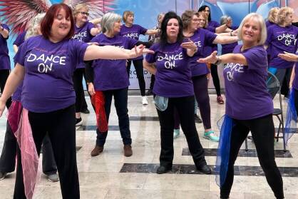 A group of women in purple Dance On T-Shirts perform in a shopping centre