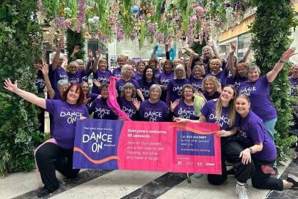 A group of women in purple Dance On T-Shirts pose in a shopping centre