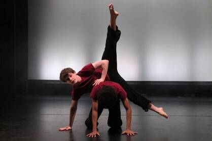 Two boys perform a counter balance on stage