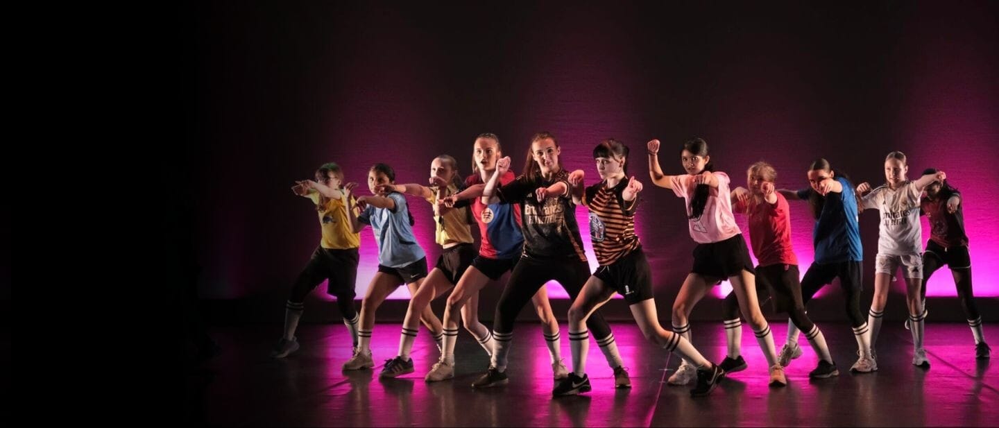 A gourp of young people dance in football kits