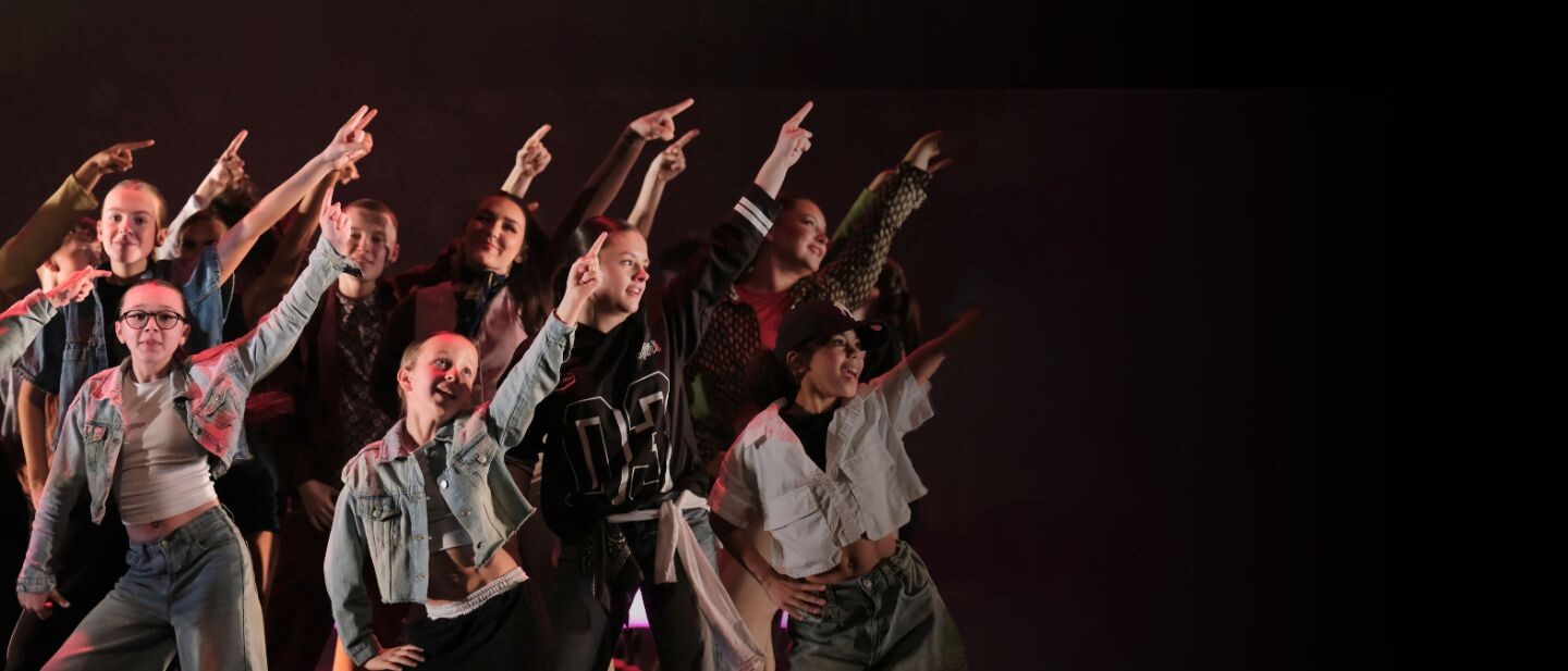 A group of young people dance pointing their fingers in the air