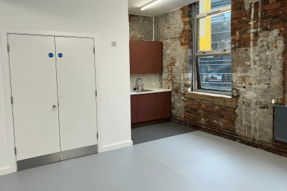 A kitchenette in the corner of a room with exposed brickwork