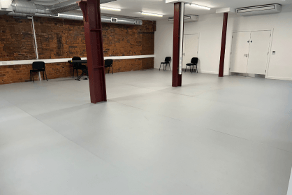 A large empty studio with pale grey dance floor